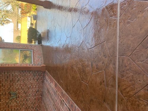 Outdoor patio with stamped stone flooring and adjacent brick wall with butterfly decoration.