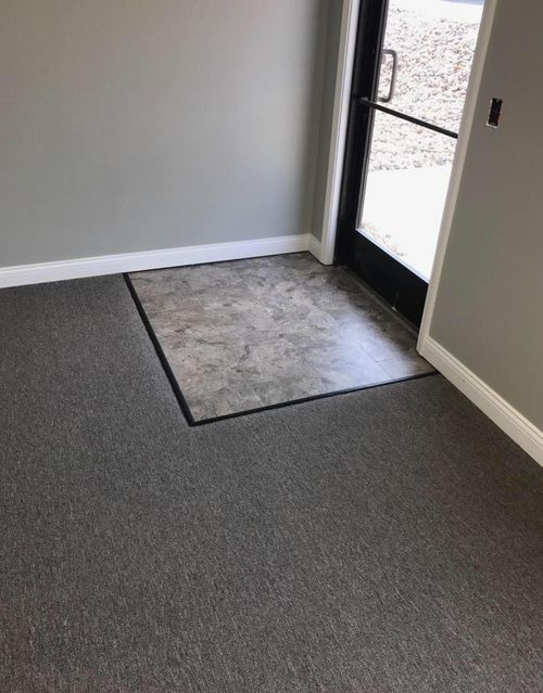 Entryway with gray carpet flooring and a small section of gray tile flooring near a glass door.